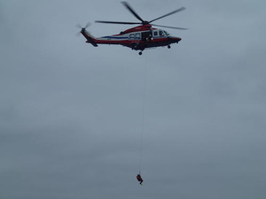 ホイスト装置を使用しヘリコプターから隊員が湖面へ降下しています