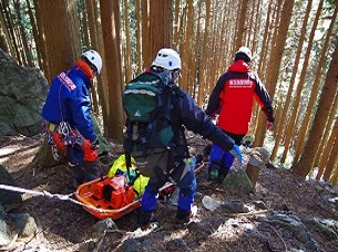 傷病者を担架に乗せて山道を搬送している写真