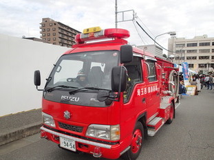 子供用防火衣を着た子供が消防車に乗車している様子