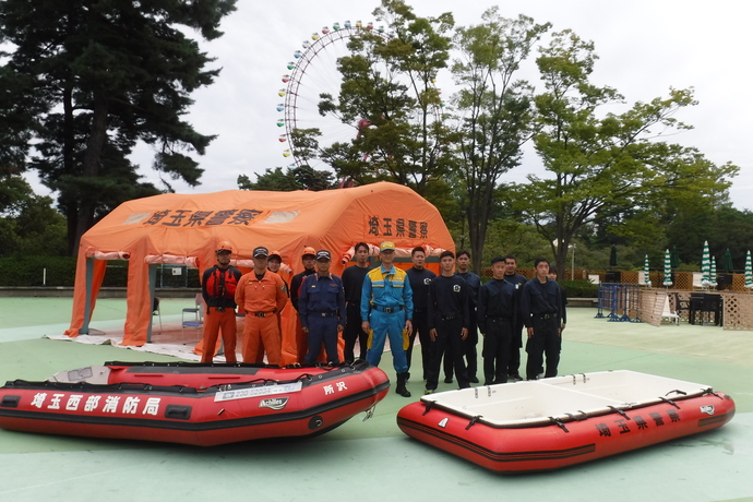 西武ゆうえんちの観覧車を背景に消防職員5名、警察職員9名が写っている集合写真