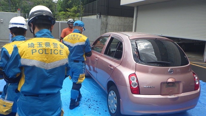 警察職員が施錠された車両の窓を警棒で破壊する写真