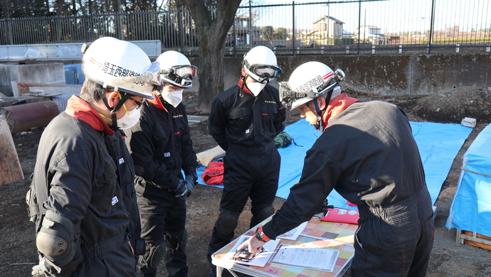 倒壊建物の前で指揮台を使用して進入管理について指導している写真