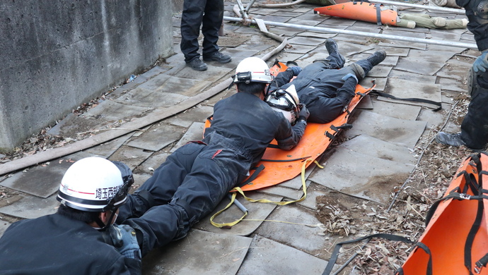 隊員2名が要救助者1名をスケッドストレッチャーに収容している写真