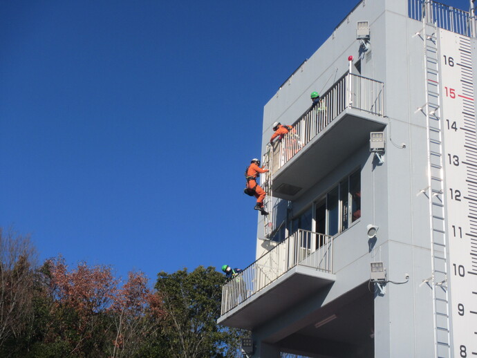 隊員がかぎ付きはしごを使用し下階へ進入している様子