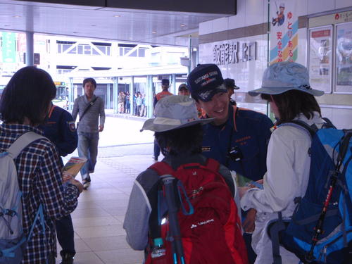 山岳救助隊員が登山客に、山岳事故防止リーフレットを配っている様子。